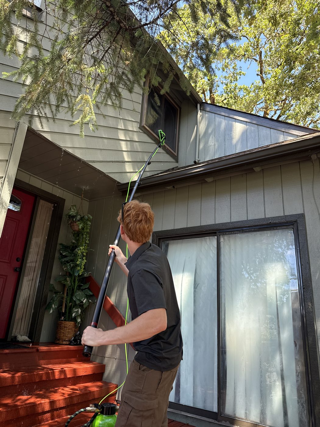 Hayden cleaning a second-story window with a water-fed pole